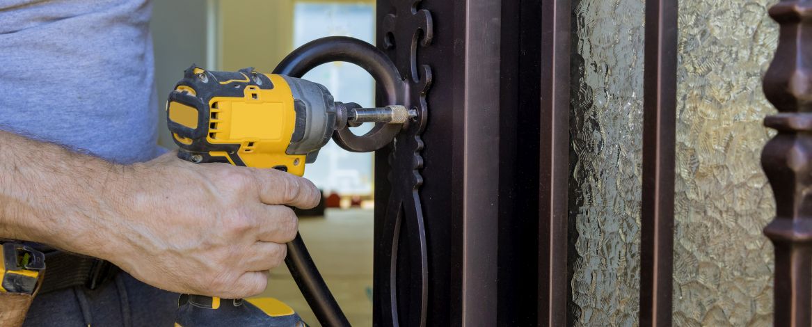 Locksmith in installing new house door lock hand holds the screwdriver